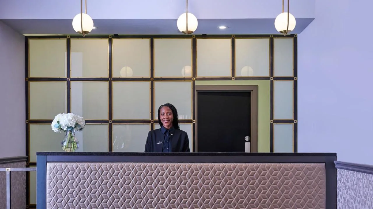 a woman standing behind the reception counter at Fraser Suites Glasgow in Glasgow